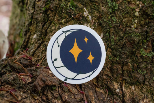 Image of Midnight Trinkets Logo sticker on a tree