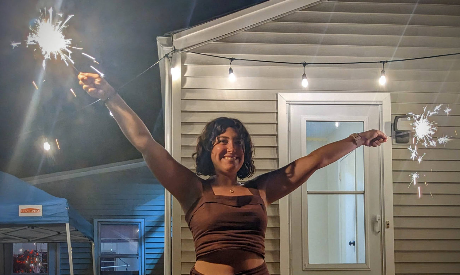 Kristen holding two sparklers at night in a backyard.